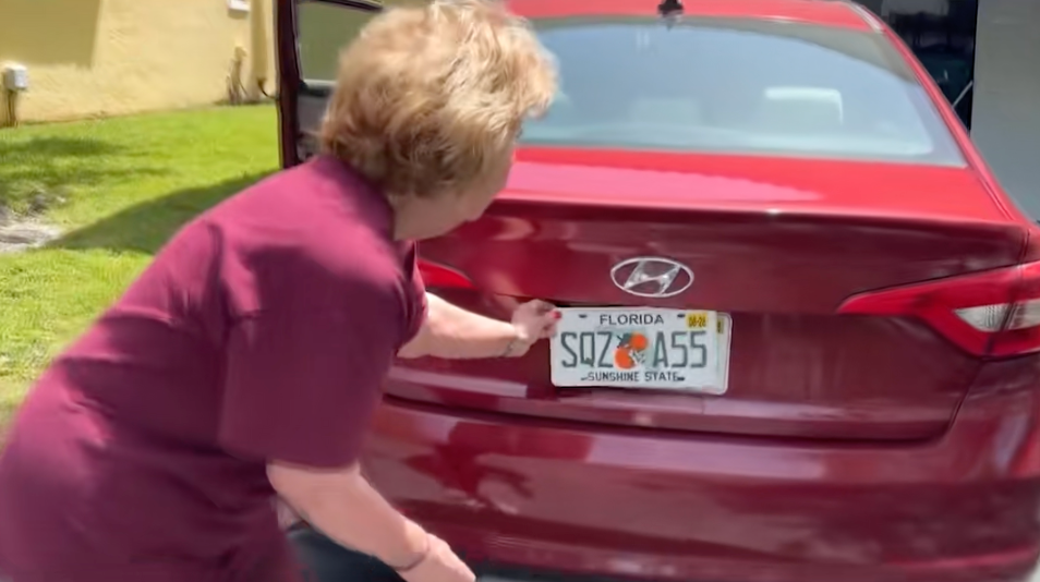 A idiosyncratic places a "SQUIRREL ASS" novelty licence sheet connected the backmost of a reddish Hyundai car successful a driveway