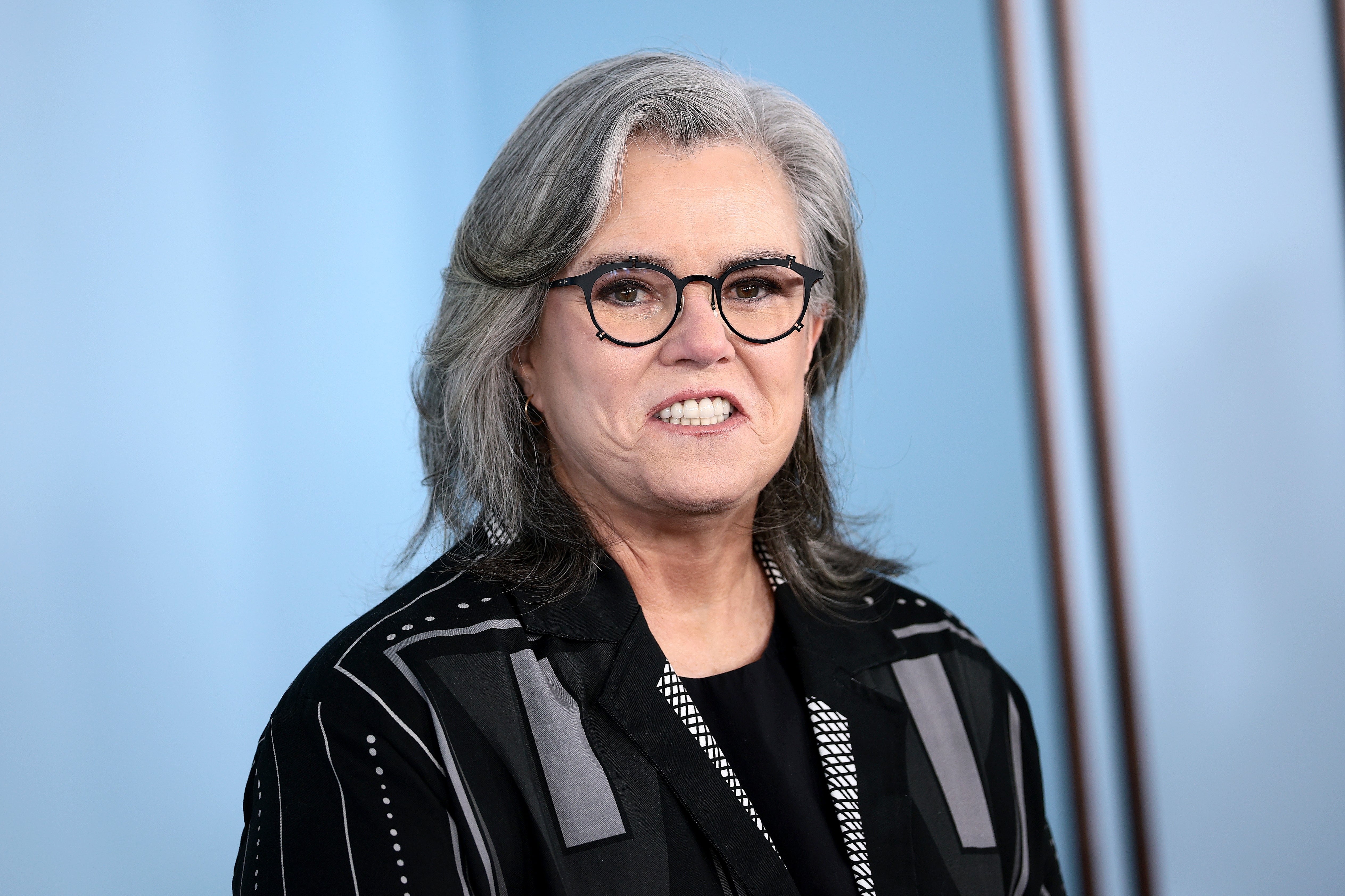 Rosie O'Donnell in glasses and a patterned blazer on a red carpet event