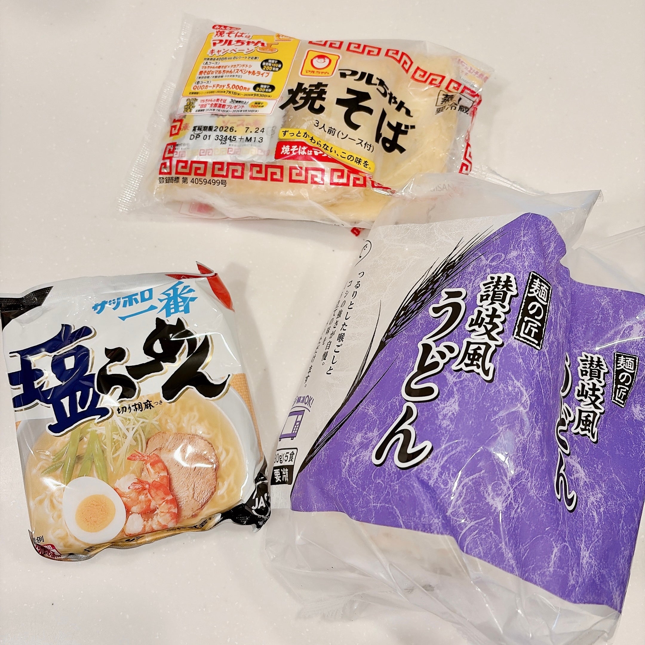 テーブルに置かれた袋麺、焼きそば、冷凍うどんのパッケージ。