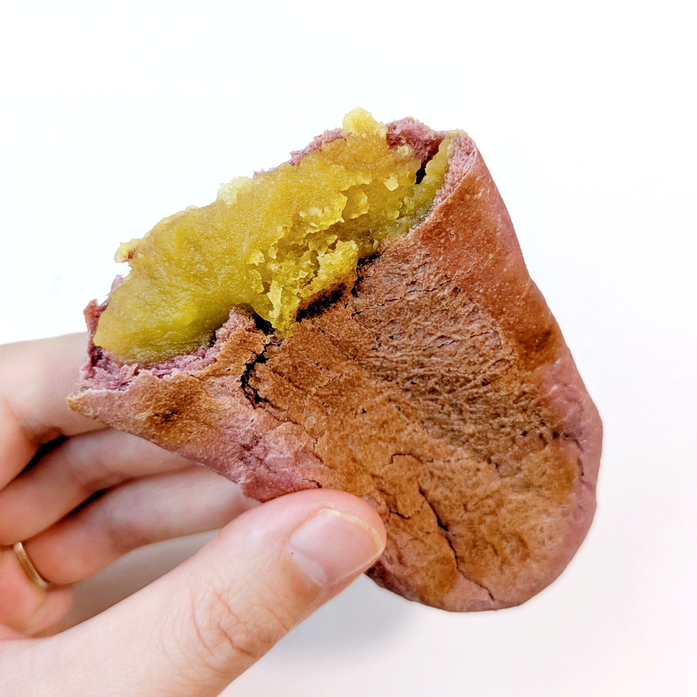 タリーズコーヒー「サツマイモパン」片手で焼いたサツマイモパンを持っている。