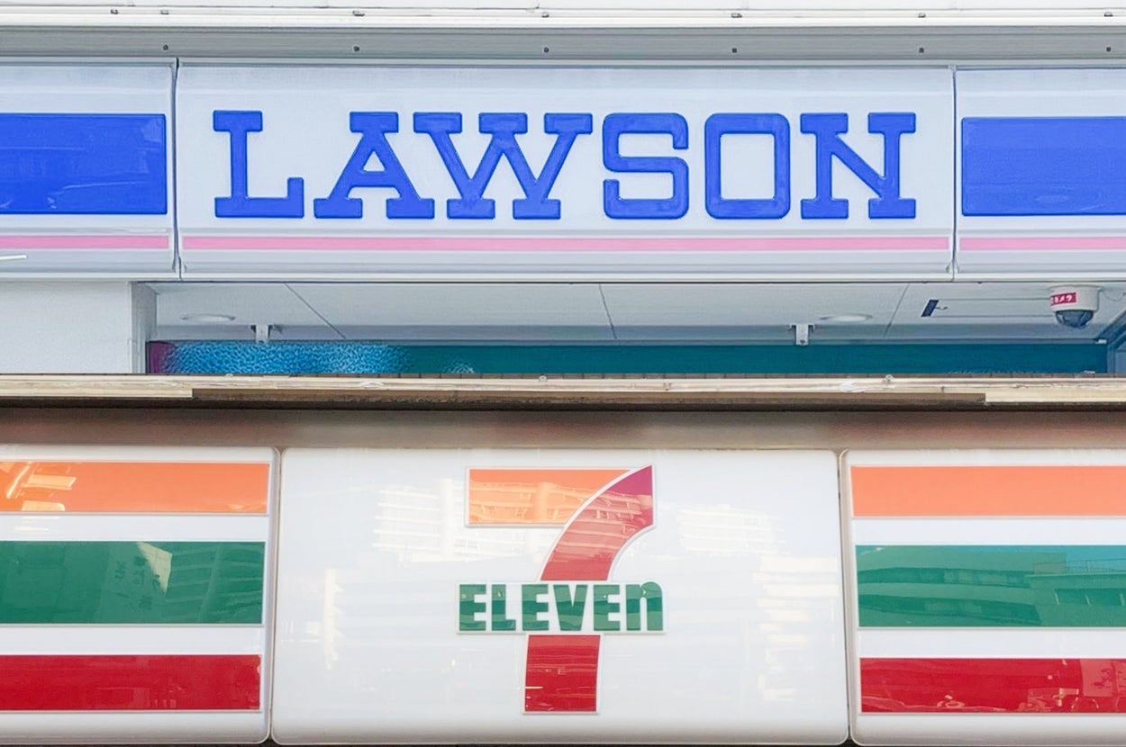 コンビニのファザードに「LAWSON」と「7-Eleven」のロゴが並んで配置されている。