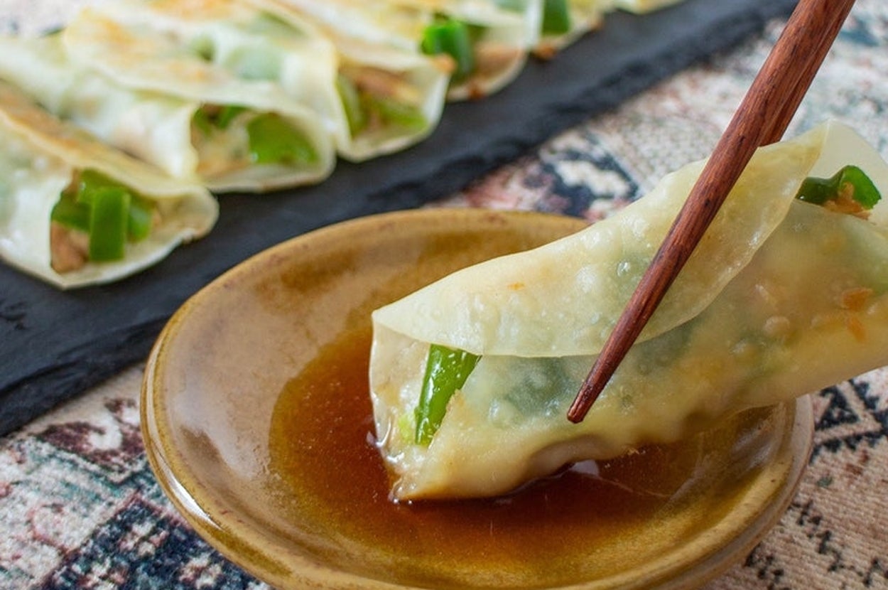 餃子が小皿のタレに浸され、他にも餃子がトレイに並ぶ。