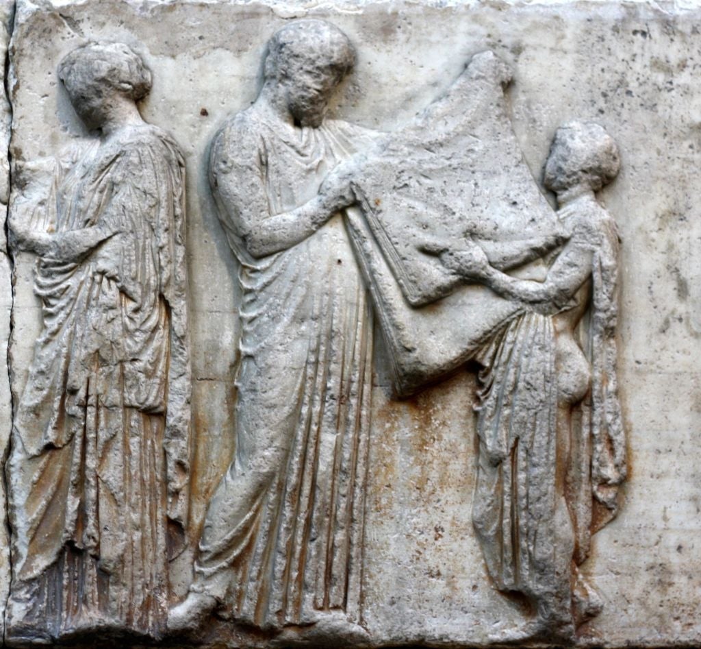 Ancient Greek relief showing three draped figures in a ceremonial scene, one holding a folded cloth