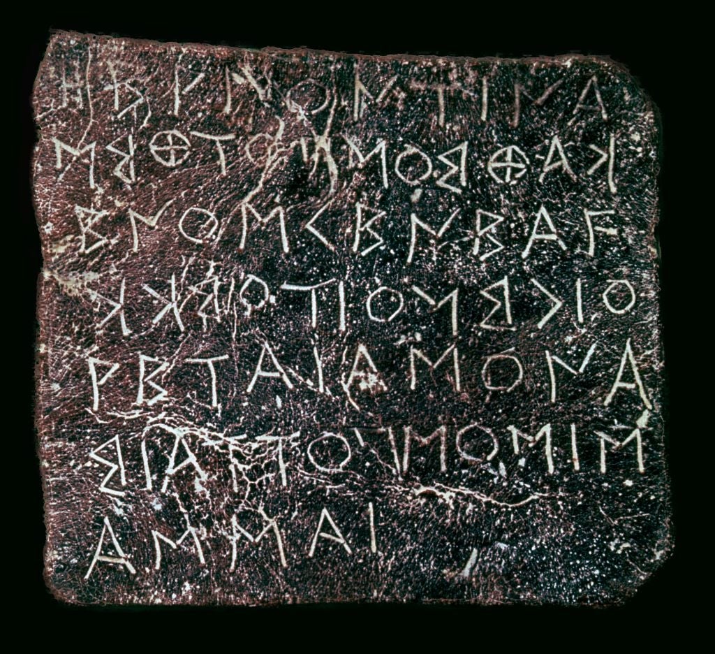 Ancient stone tablet with engraved text in a historical script, featuring various symbols and characters
