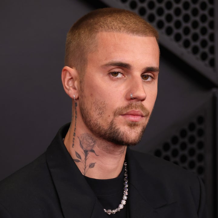 Justin Bieber in a suit with a rose neck tattoo at a formal event, wearing a necklace and nose ring