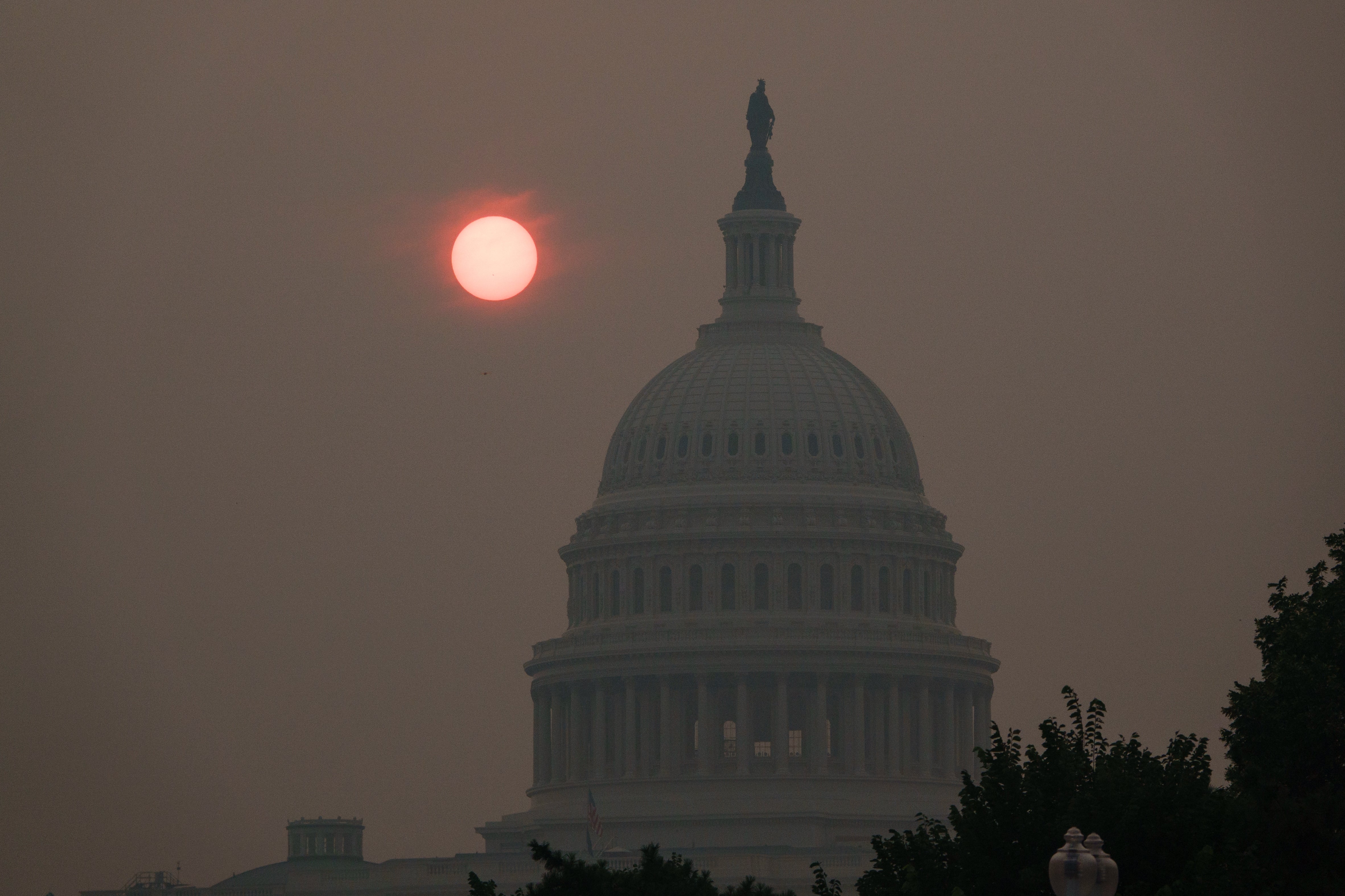 US Capitol-bygningen er silhuett mot en disig himmel med en sol skjult av røyk, noe som indikerer dårlig luftkvalitet