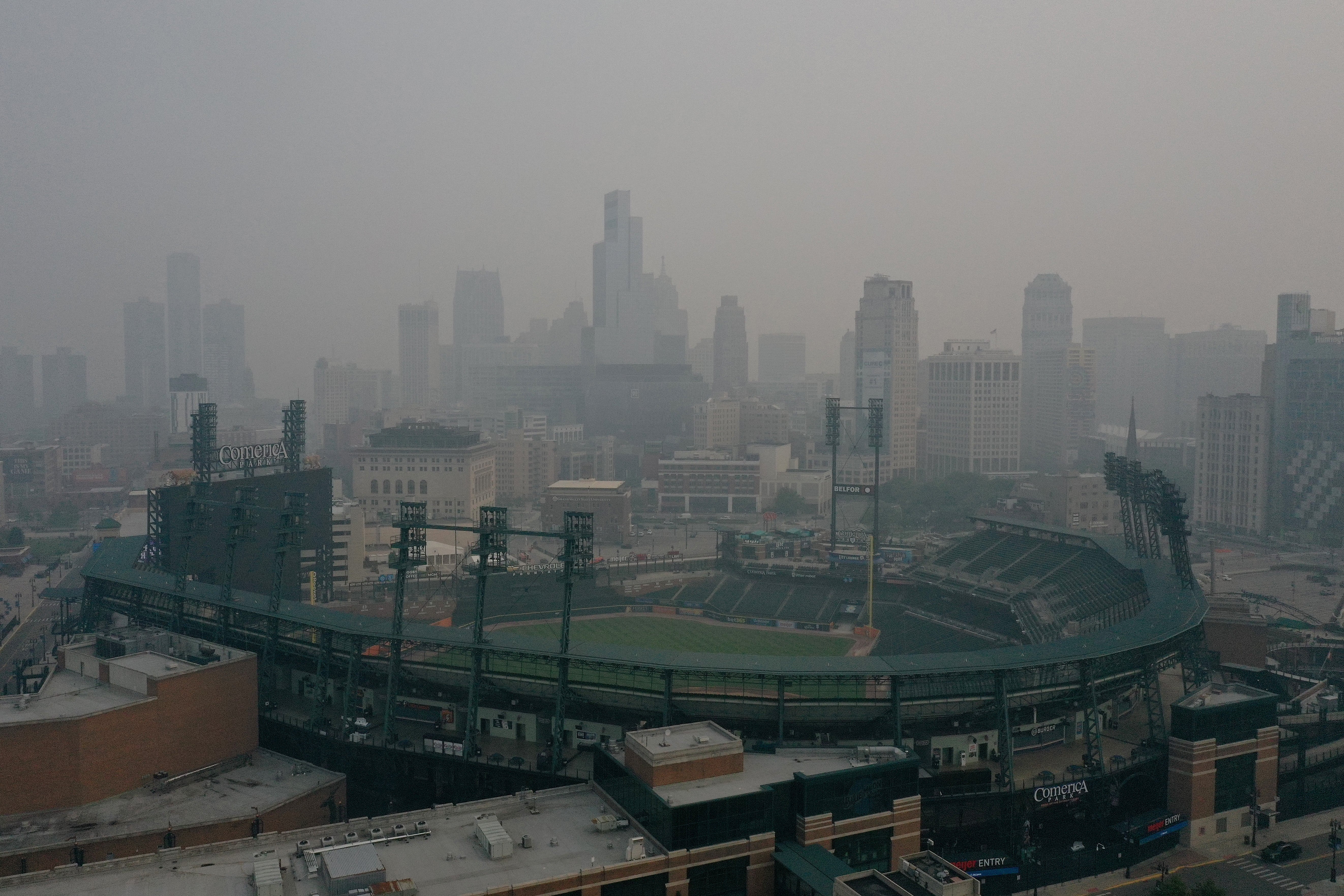 Byens skyline innhyllet i dis; en baseballstadion er synlig i forgrunnen