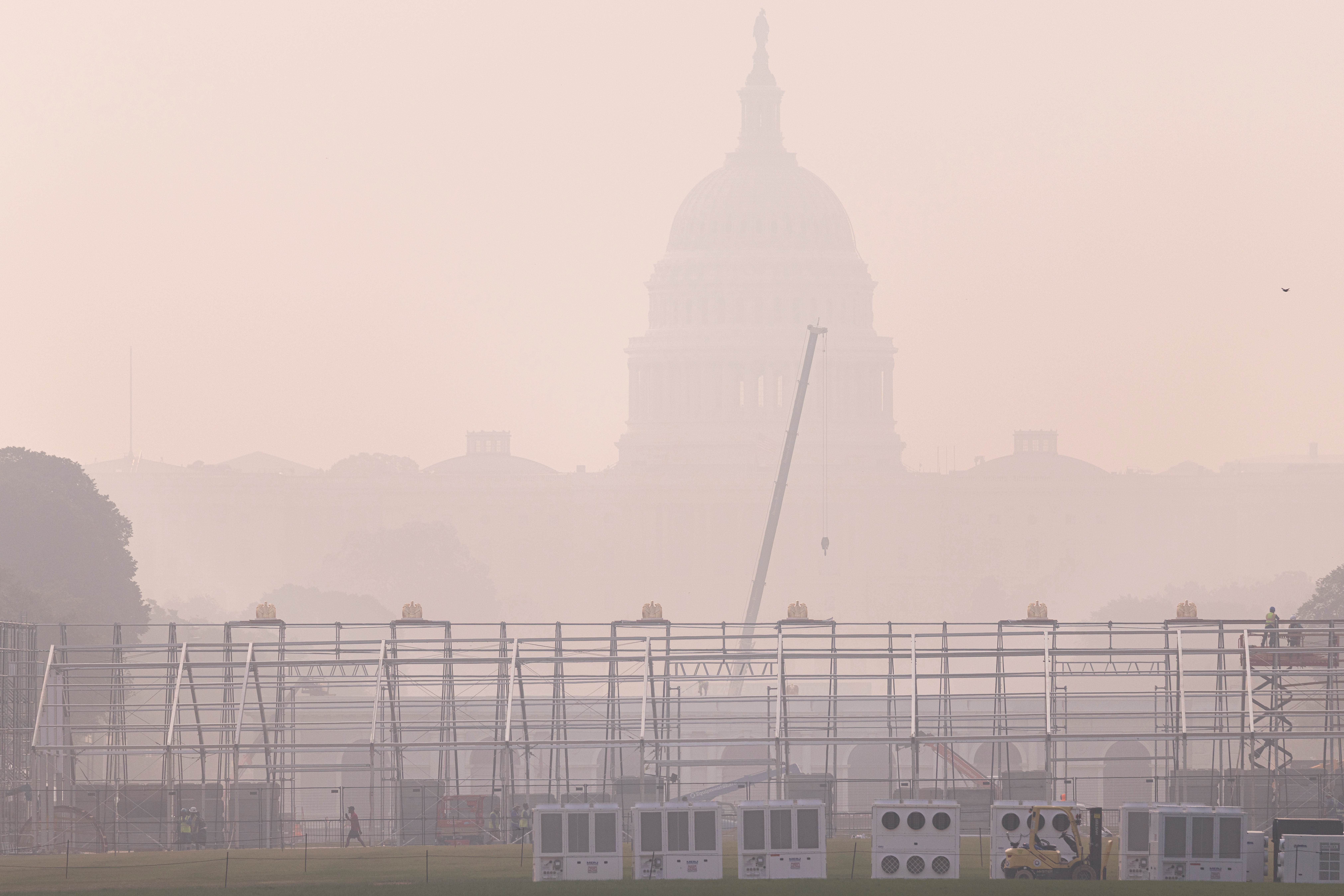 US Capitol innhyllet i kraftig røyk, med stillaser og en kran i forgrunnen, som indikerer konstruksjon eller arrangementsoppsett