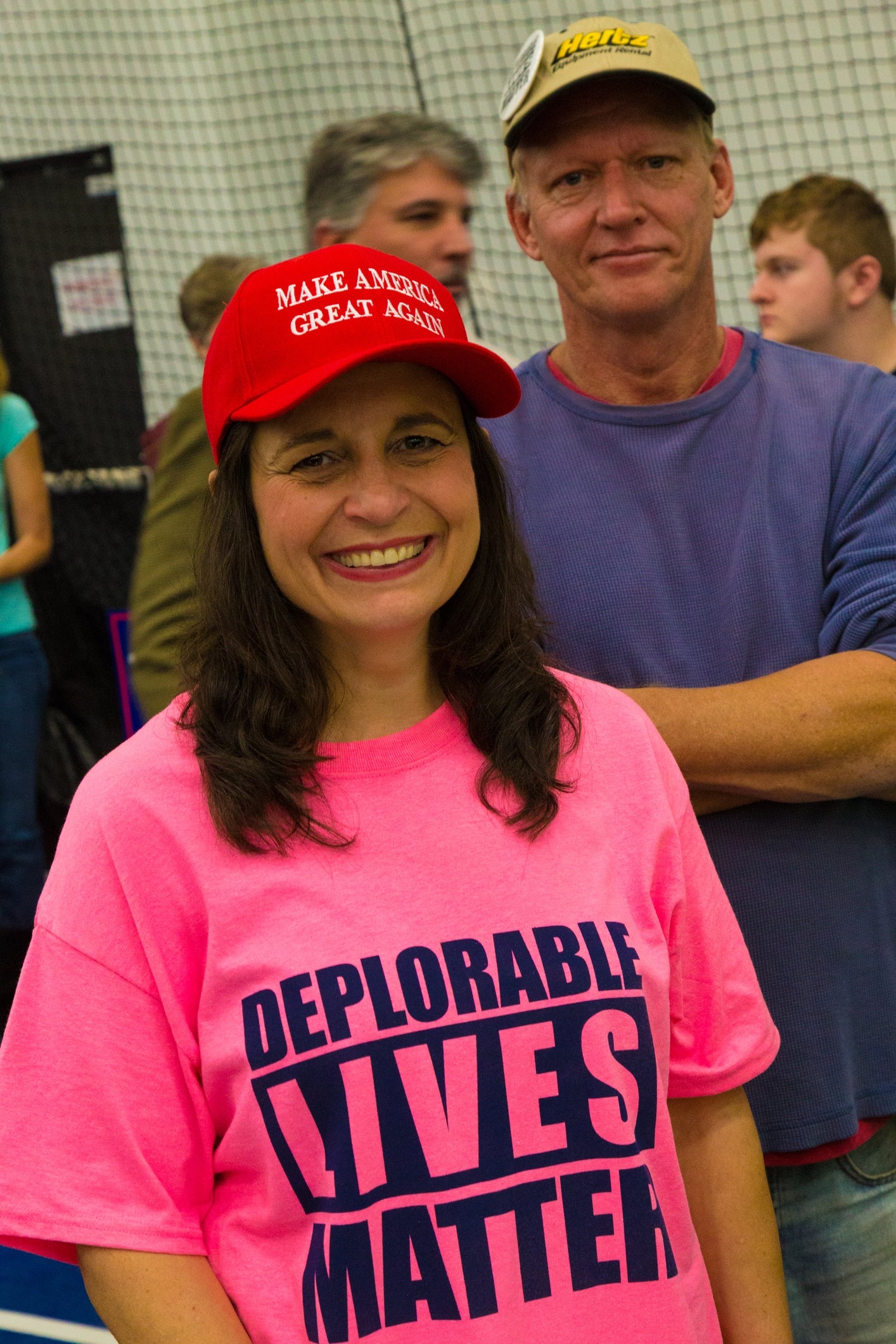 Person som smiler i "Deplorable Lives Matter" skjorte og "Make America Great Again" hatt, stående i en uformell innendørs setting
