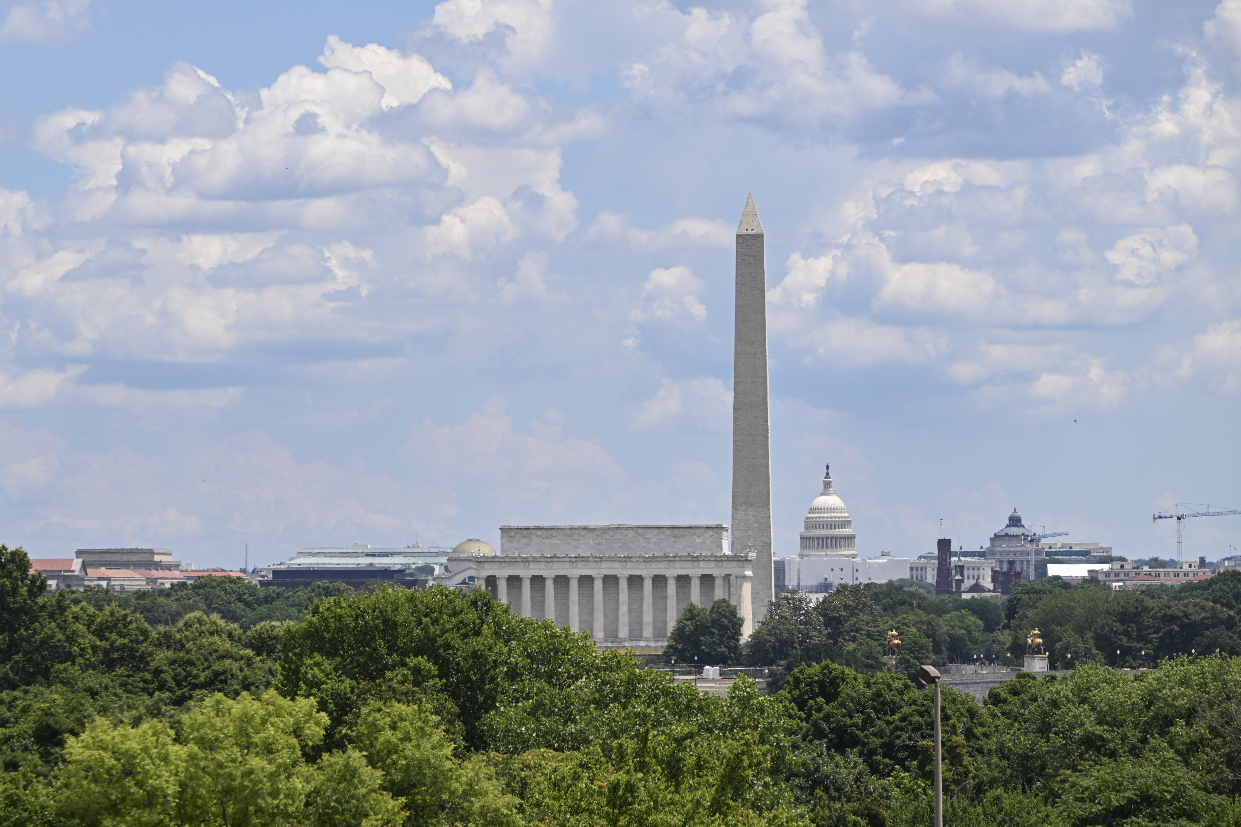 Washington Monument og Lincoln Memorial med Capitol i det fjerne, omgitt av grøntområder og under en delvis overskyet himmel