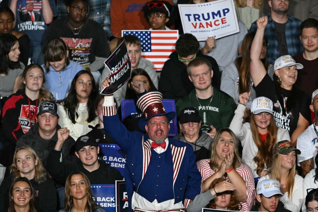 En folkemengde på et rally, med en mann i et patriotisk antrekk med en topplue, som holder et skilt som støtter det andre endringsforslaget