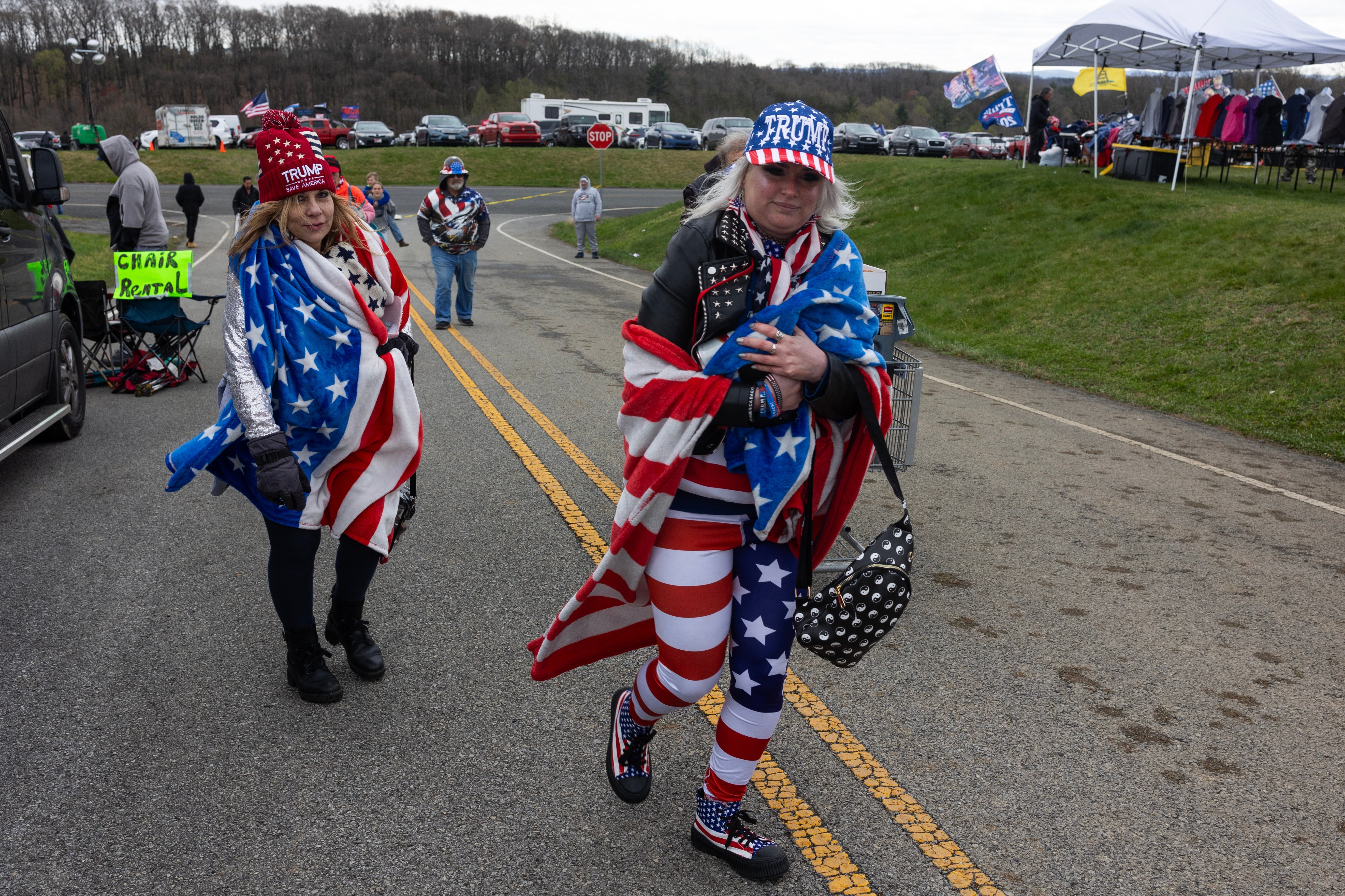 To personer er drapert i amerikanske flagg mens de går. Man har på seg en piggete skinnjakke; begge har matchende hatter og antrekk med patriotisk tema