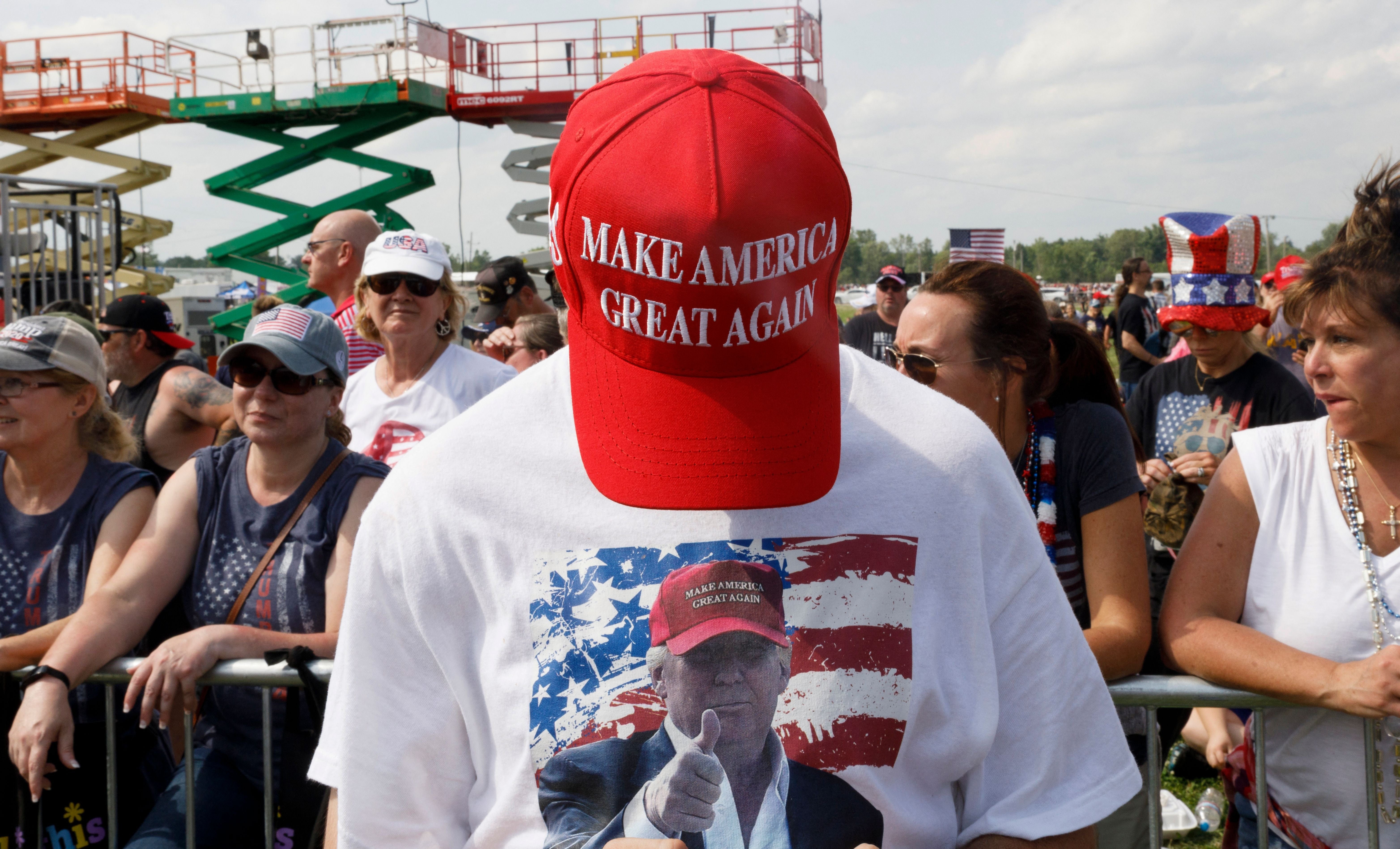 Person i en "Make America Great Again" hatt og Trump-skjorte på et stevne, omgitt av en folkemengde