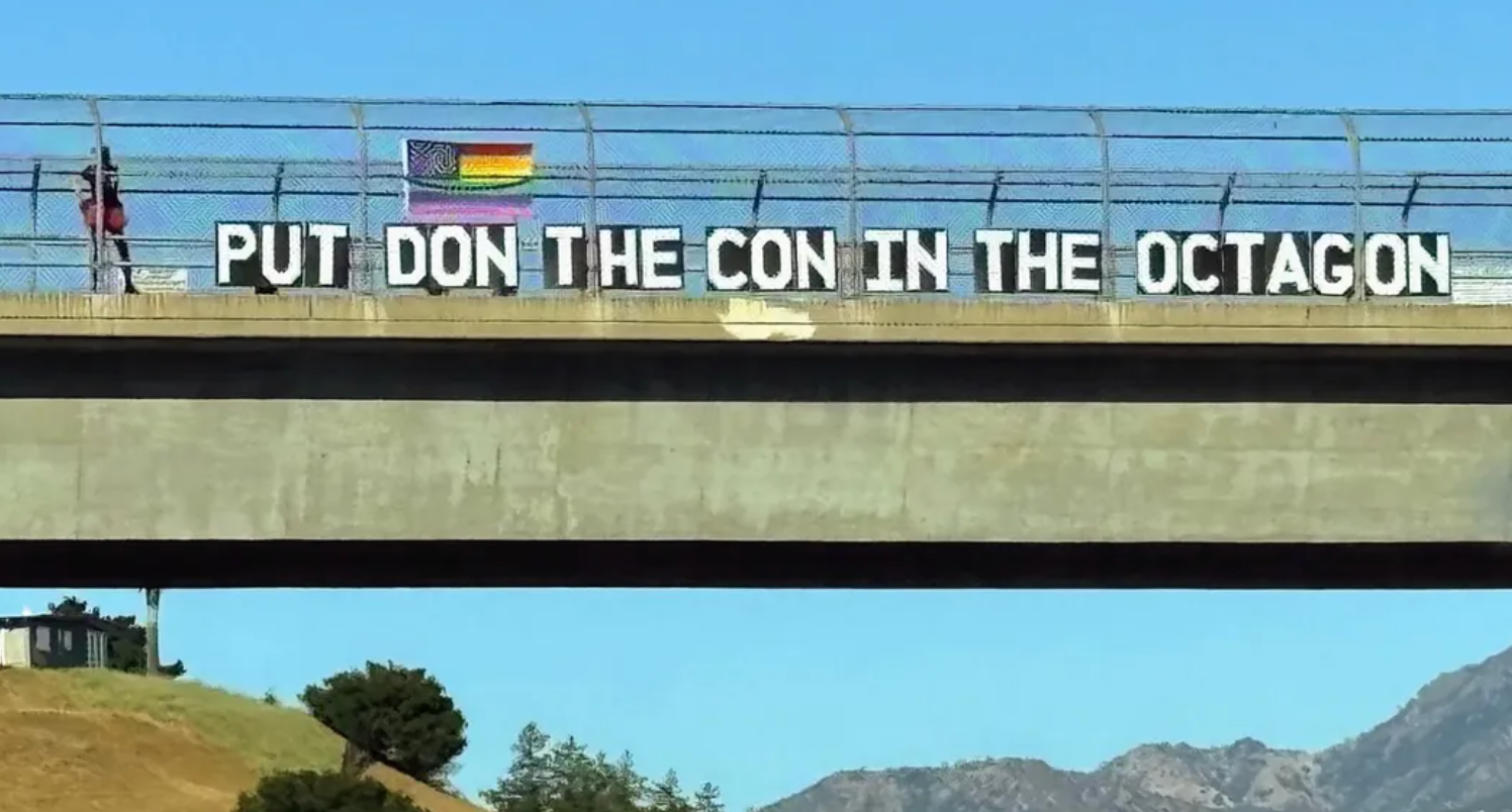 Broskilt med regnbueflagget lyder: "PUT DON THE CON IN THE OCTAGON."