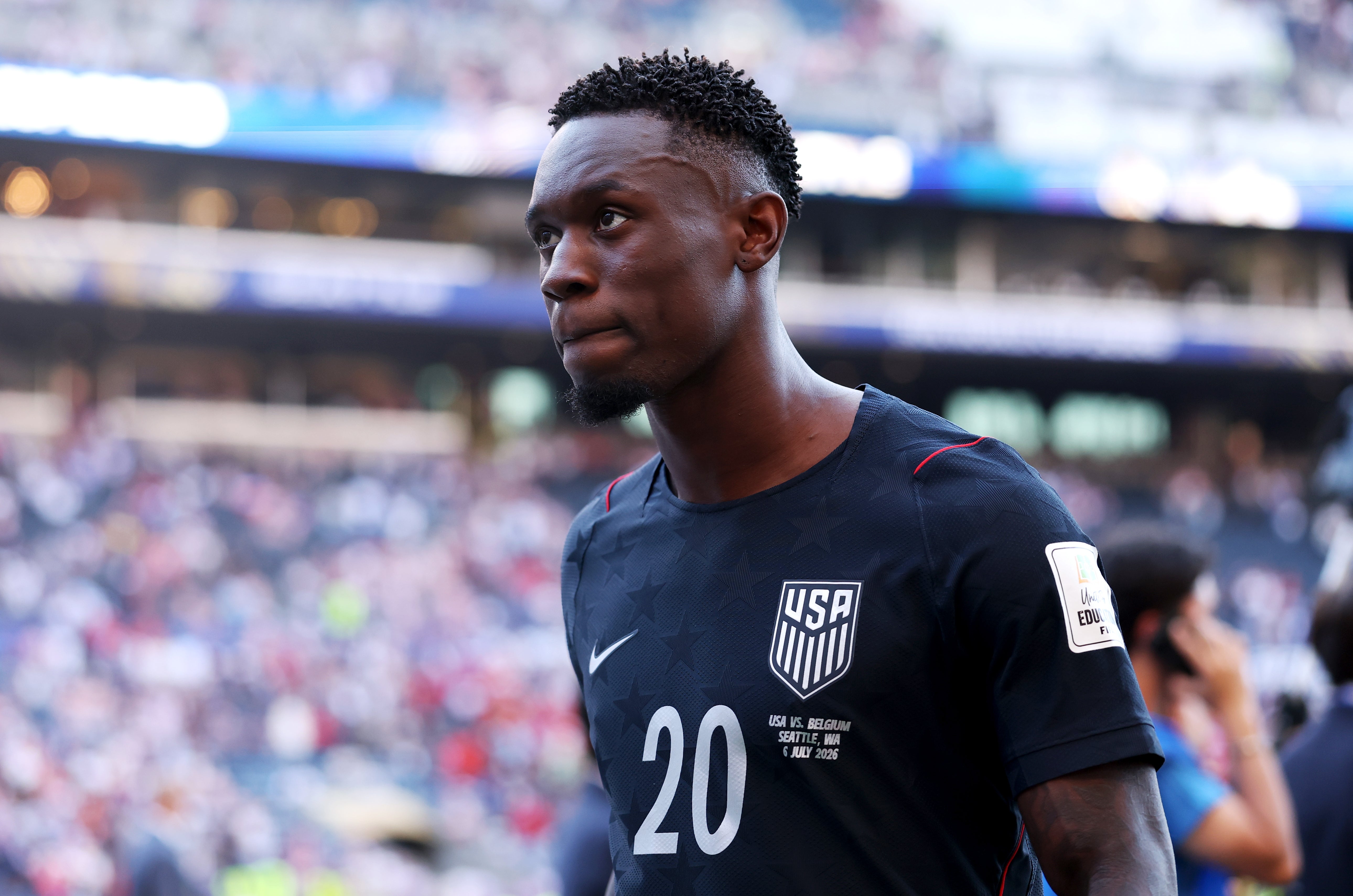 Fotballspiller i USA-trøye nummer 20, går på banen under en kamp, med et fokusert uttrykk