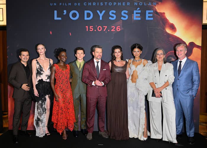Cast of "L'Odyssée" on red carpet; diverse styles from formal suits to elegant gowns