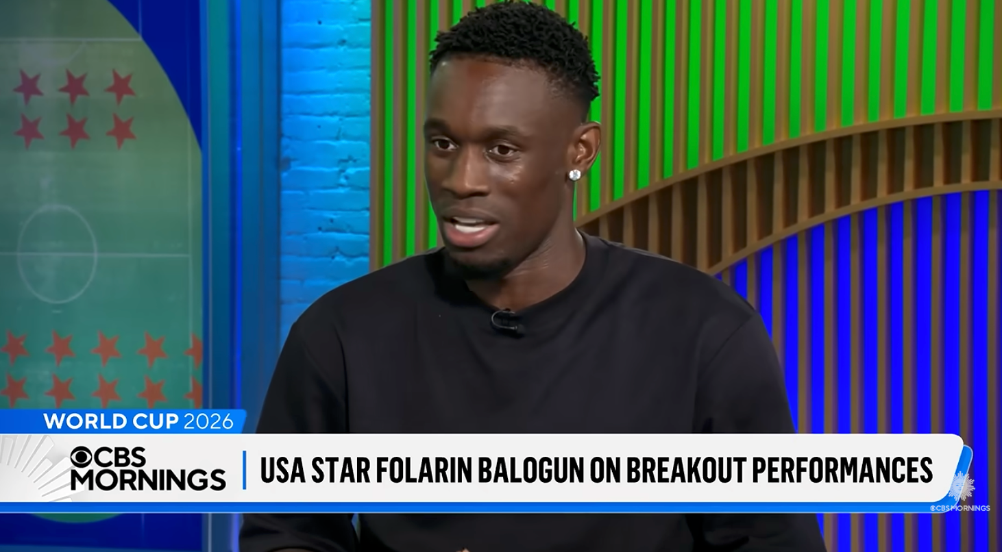 Fotballspiller i et TV-intervju som diskuterer opptredener; nederste tredjedel av teksten nevner USA-stjernen Folarin Balogun på breakout-opptredener, World Cup 2026