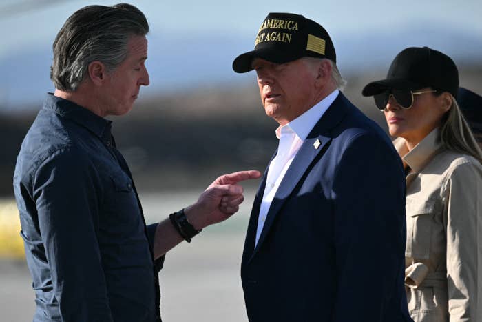 Person gesturing while talking to another person wearing a "Make America Great Again" cap, with a third person in sunglasses nearby