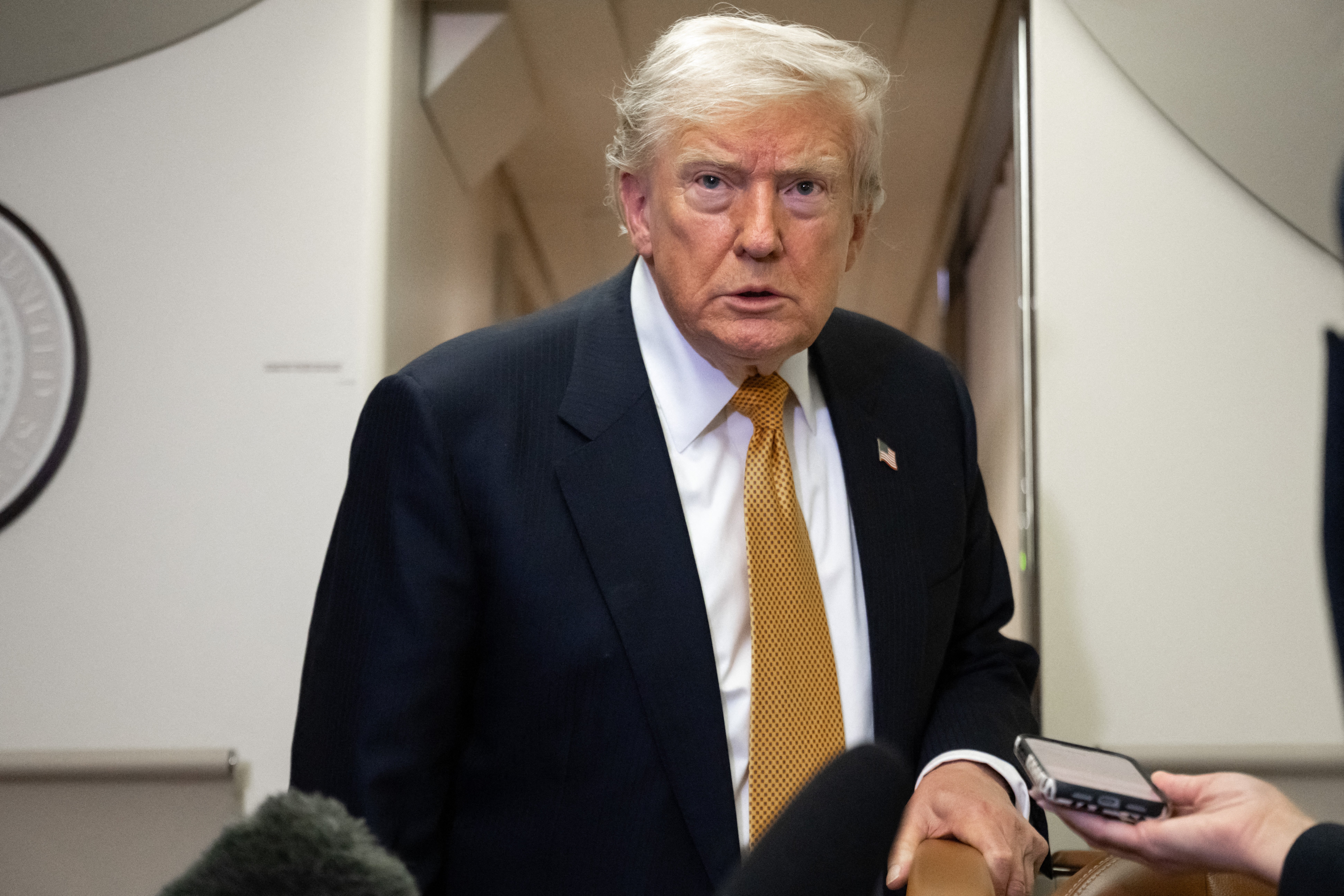 A idiosyncratic successful a suit and necktie stands successful a country with microphones nearby, suggesting a property lawsuit oregon interrogation setting