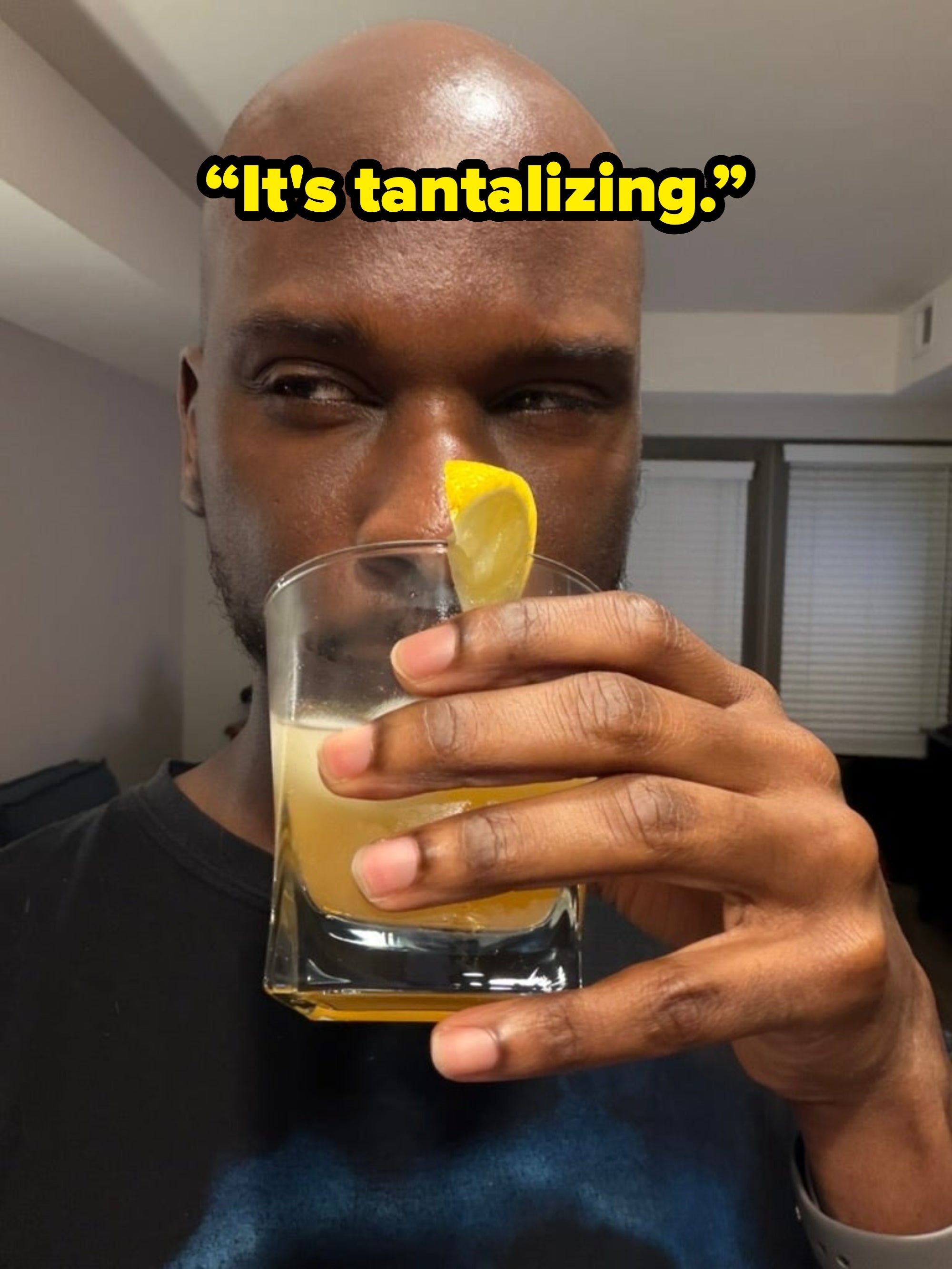 Person holding a cocktail with a lemon twist in a glass, gazing thoughtfully
