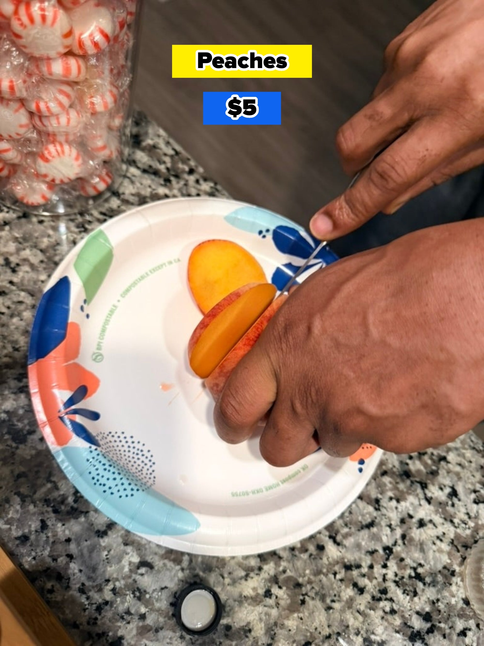 Person slicing a peach on a paper plate with candies in a container nearby