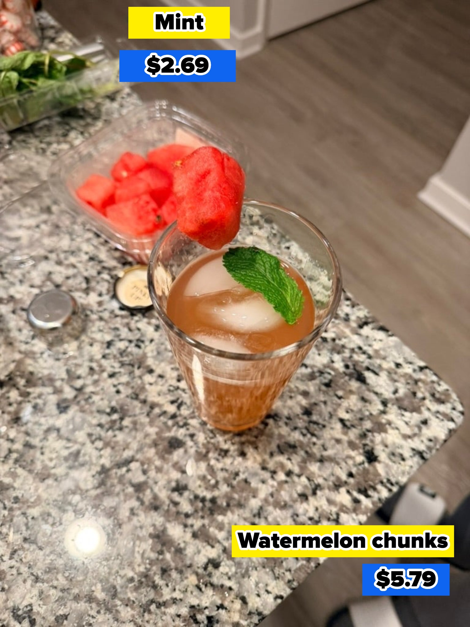 A glass of iced tea with mint on a countertop, garnished with a watermelon slice, next to a container of watermelon cubes