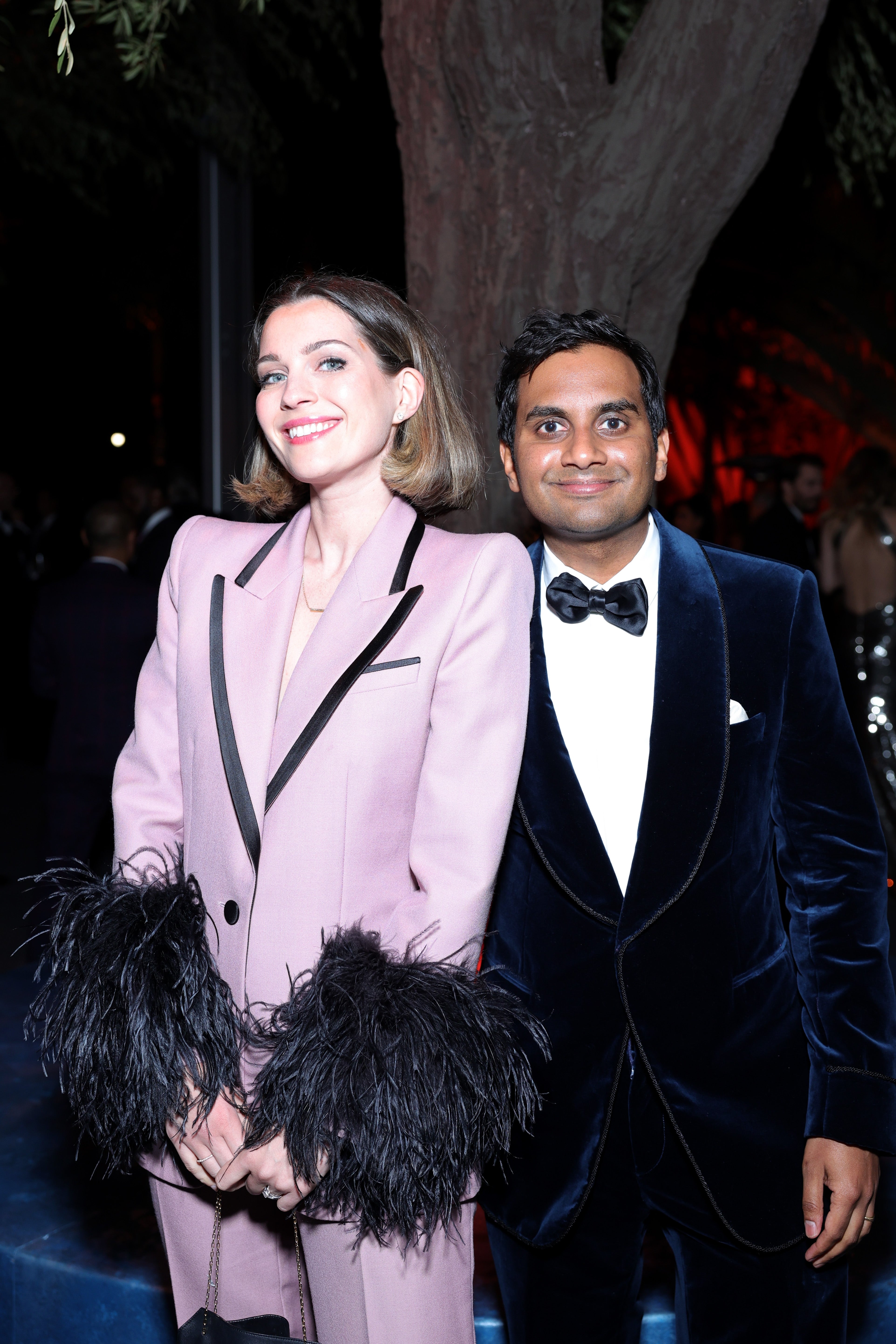 Serena Skov Campbell in a feather lined suit and Aziz Ansari in a velvet suit at an event
