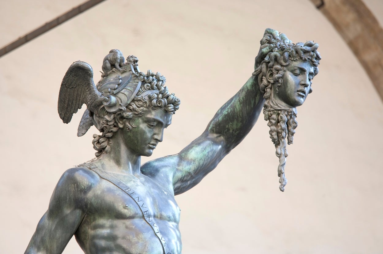 A statue of Perseus holding Medusa's head triumphantly in an outdoor setting