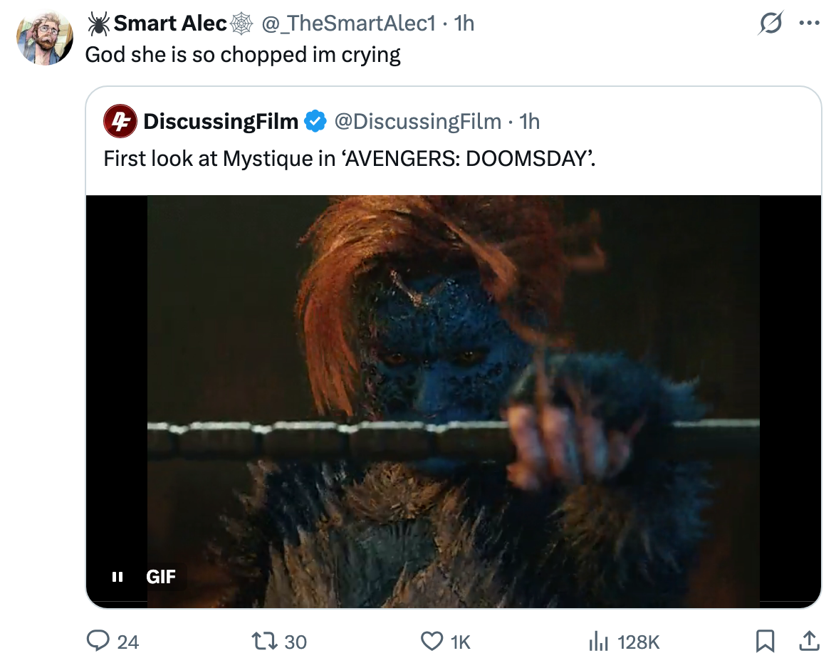 A character resembling Mystique from X-Men, with blue skin and a detailed, textured appearance, holding a bar, appears in a screenshot from a video clip