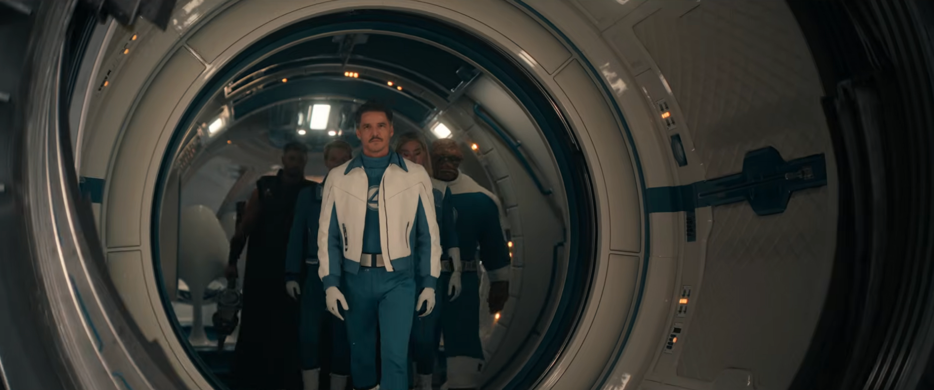 A person in futuristic blue and white attire, including a jacket and gloves, walks confidently through a spacecraft-like corridor