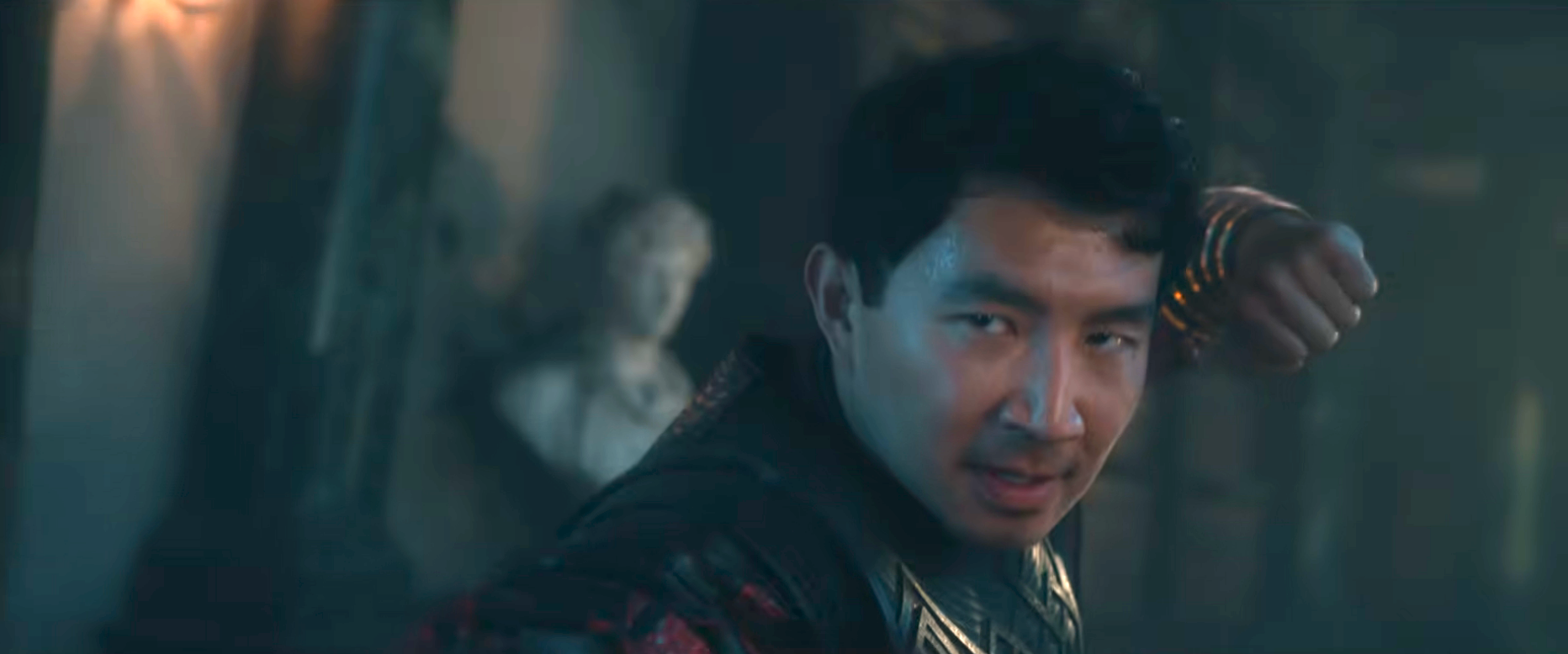 A man in a dramatic pose appears focused, wearing ornate warrior-style attire, with a blurred background suggesting an action or fantasy setting