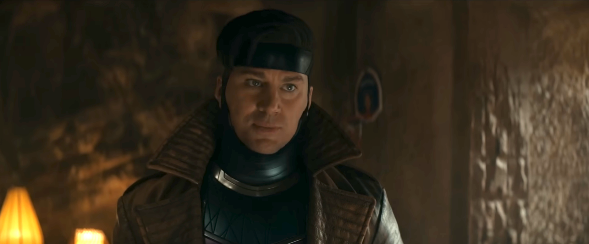 A person wearing futuristic, sci-fi clothing is in a dimly lit room, looking ahead