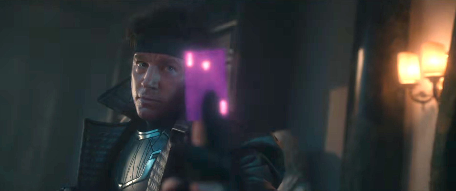 Person in futuristic armor and headband holding a glowing pink card, possibly in a dramatic scene setting