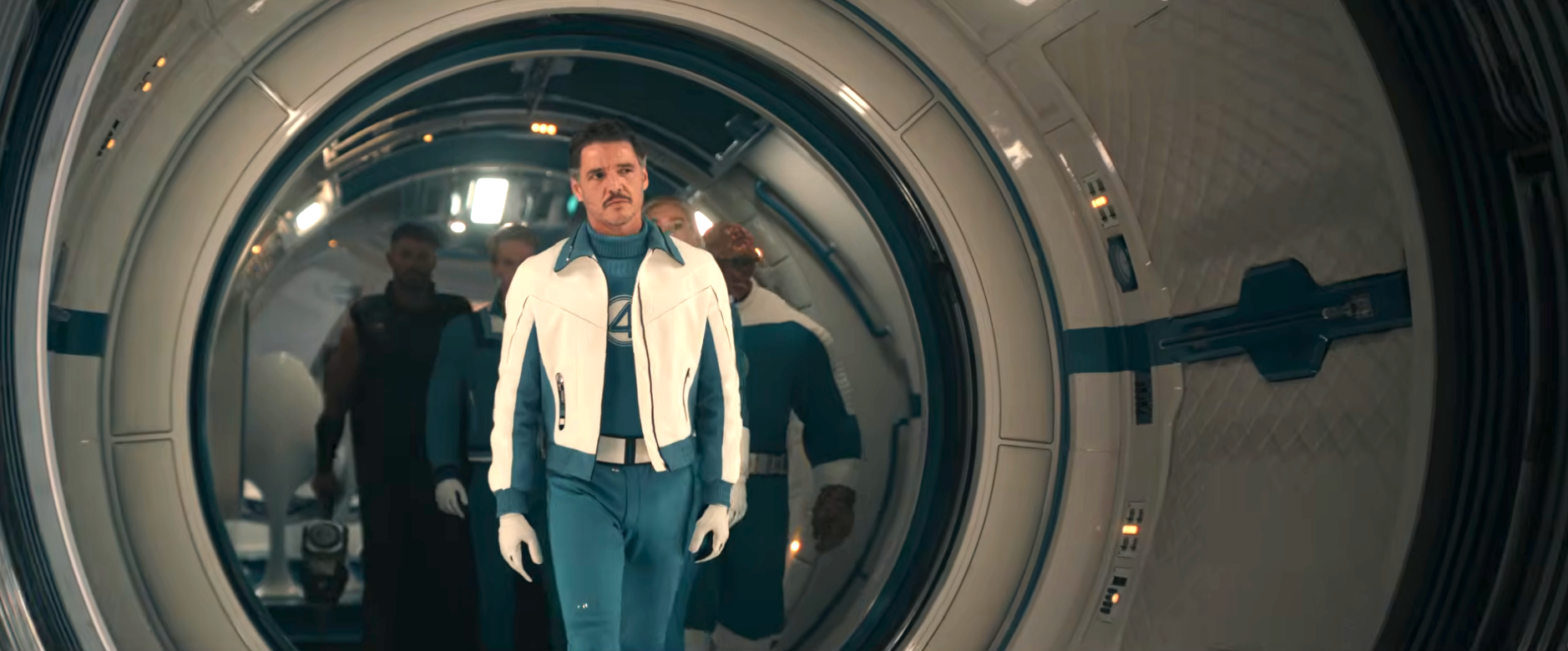 A person in a futuristic sci-fi costume, featuring a white jacket and blue jumpsuit, walks confidently through a sleek, circular corridor