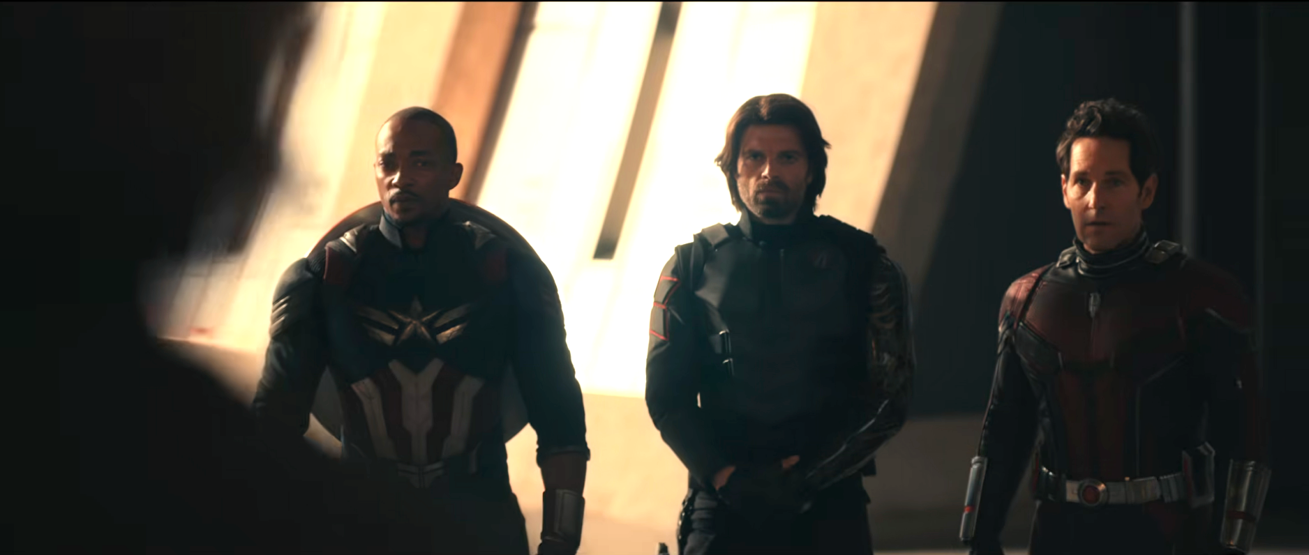 Three characters in superhero suits stand together in a dramatic setting