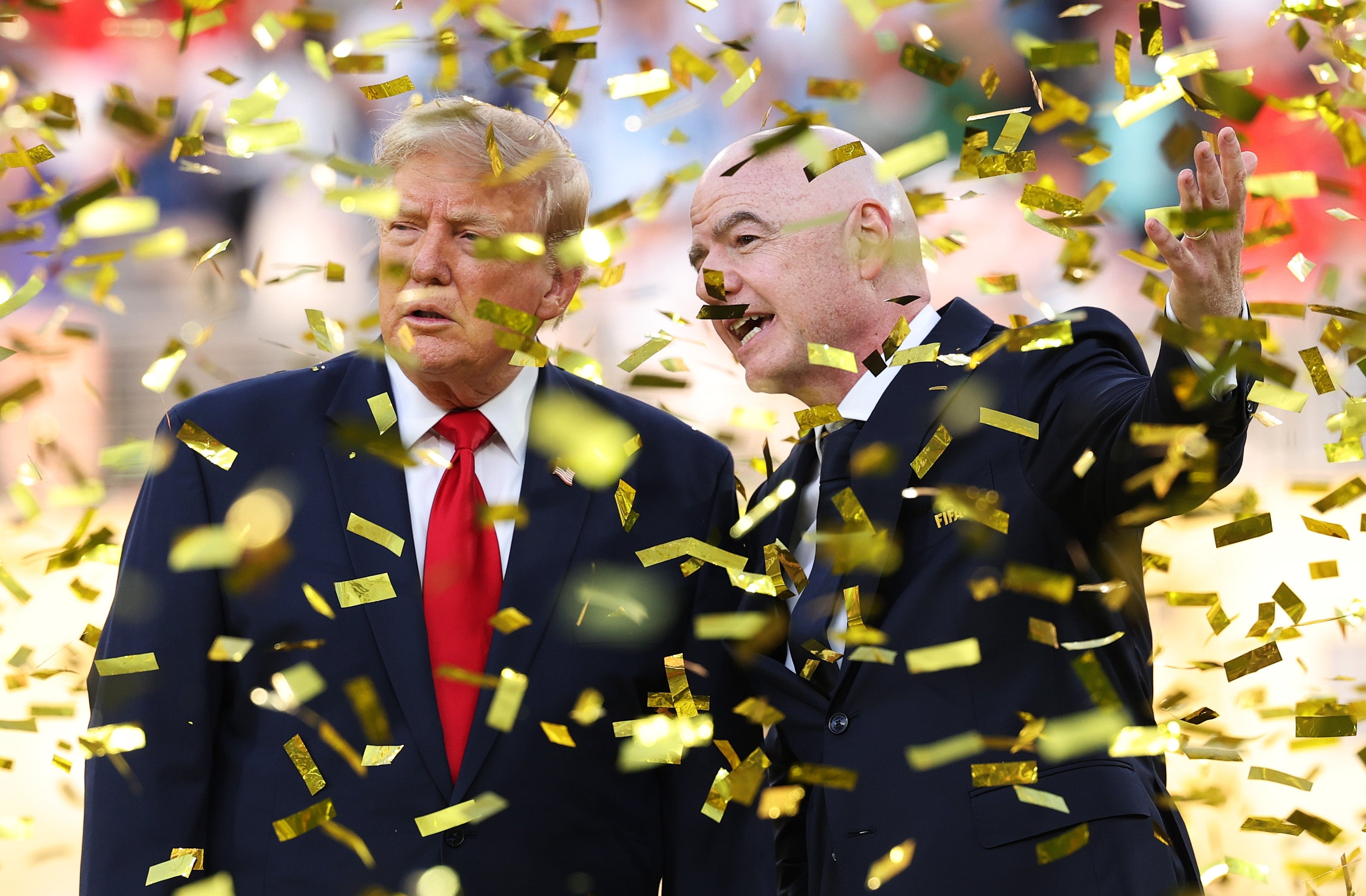 Two men in suits standing amid falling gold confetti at a sports event
