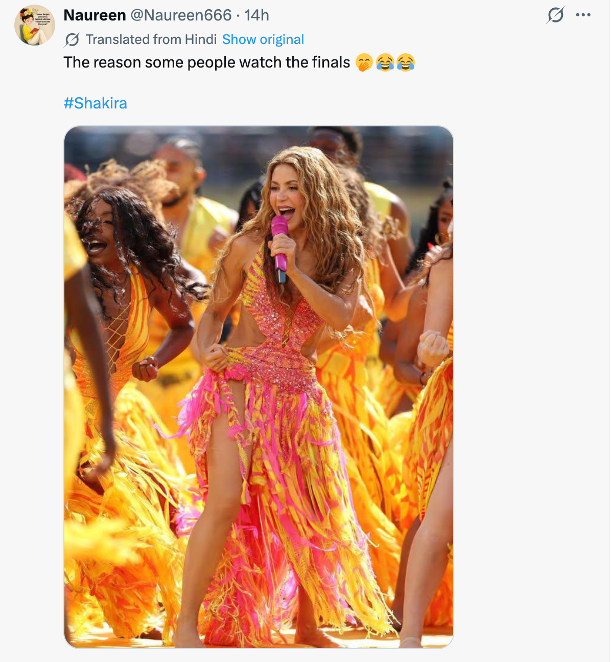 Shakira performs energetically, wearing a stylish fringed outfit, with lively dancers in the background