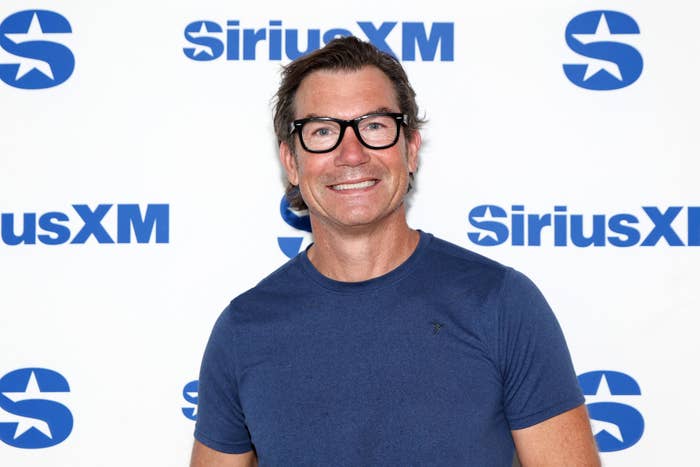 A person wearing glasses and a casual T-shirt is smiling while standing in front of a backdrop with SiriusXM logos