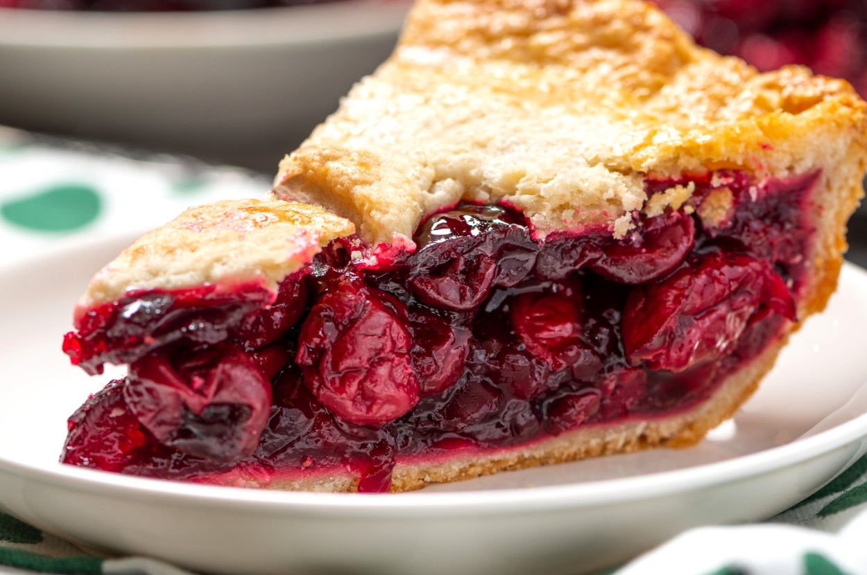 Slice of cherry pie on a plate, showcasing a flaky crust and juicy cherries