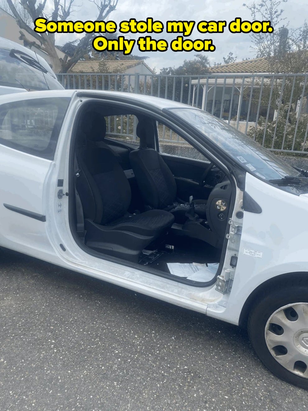 Open car door showing the front seats and interior of a parked car on a street