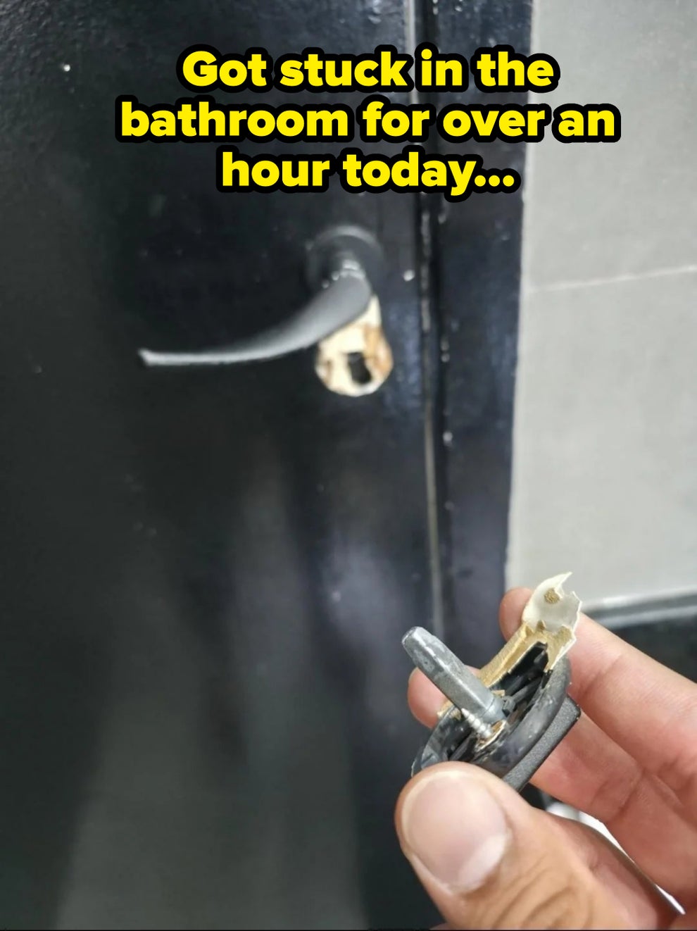 A broken door handle with visible damage, and a hand holding the detached inner mechanism