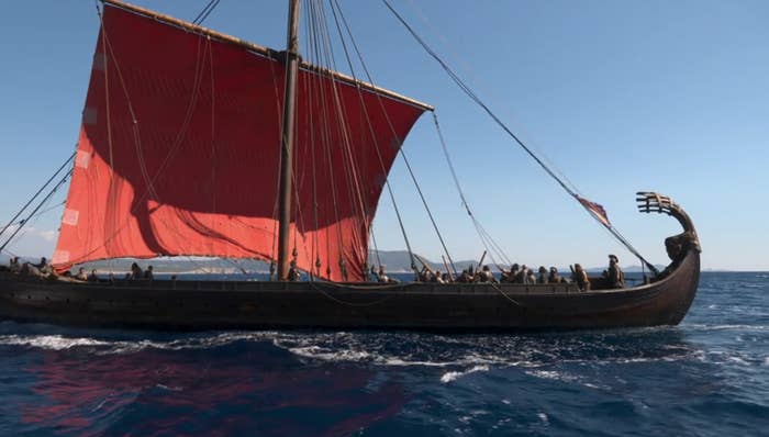 A Viking longship with a ample  sail and galore  radical   connected  committee  is sailing connected  the ocean