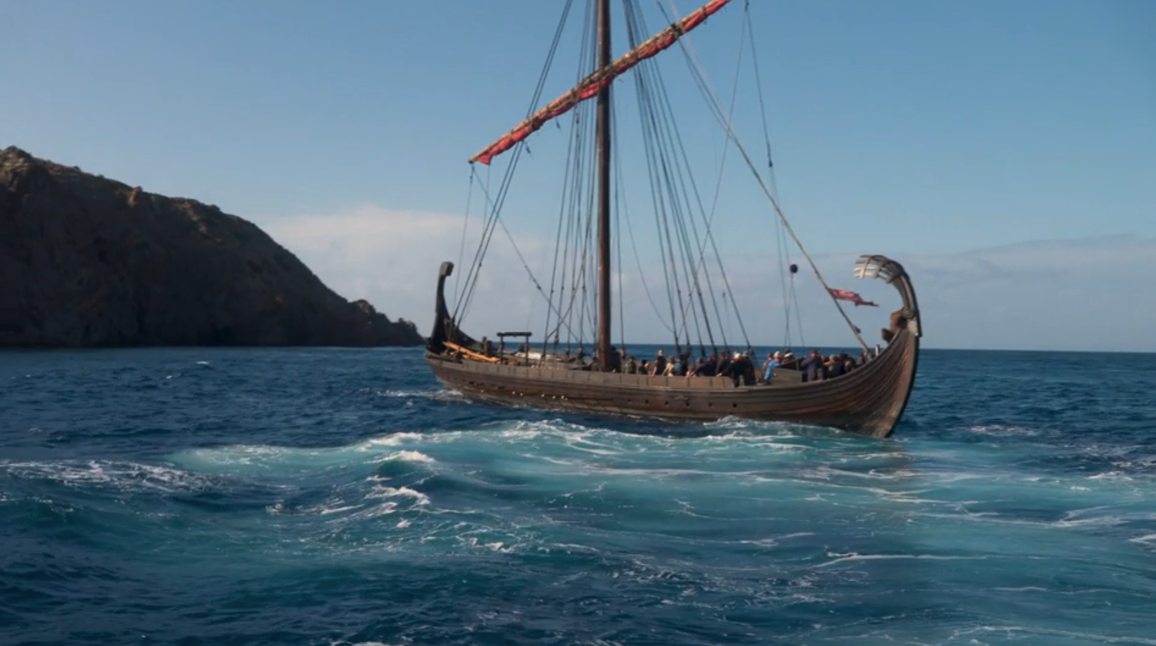 A Viking longship sails connected the water adjacent rocky cliffs, with respective radical connected committee bracing against the wind
