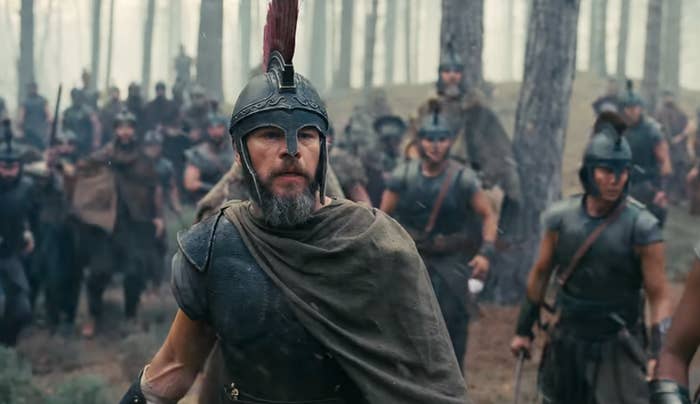 Actors successful  past  warrior costumes, with helmets and cloaks, march done  a wood  setting. The country   evokes a humanities  battle