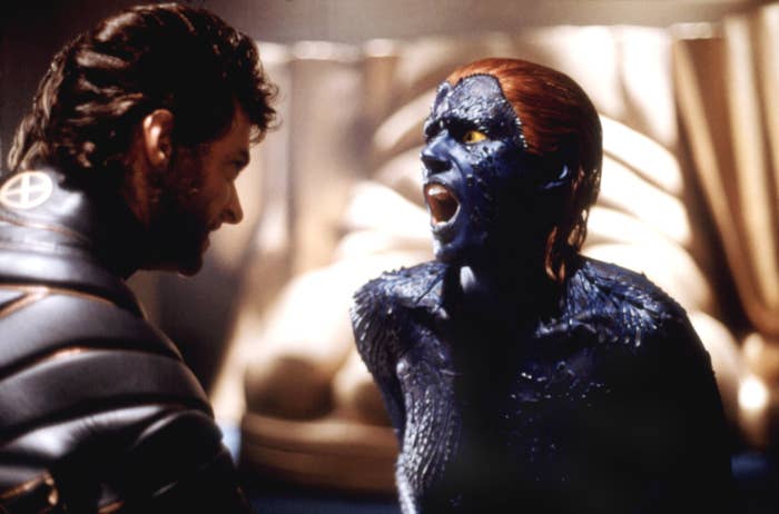 Two characters from a superhero film, one wearing dark leather with an "X," and the other with blue, textured skin, appear to be in a confrontation