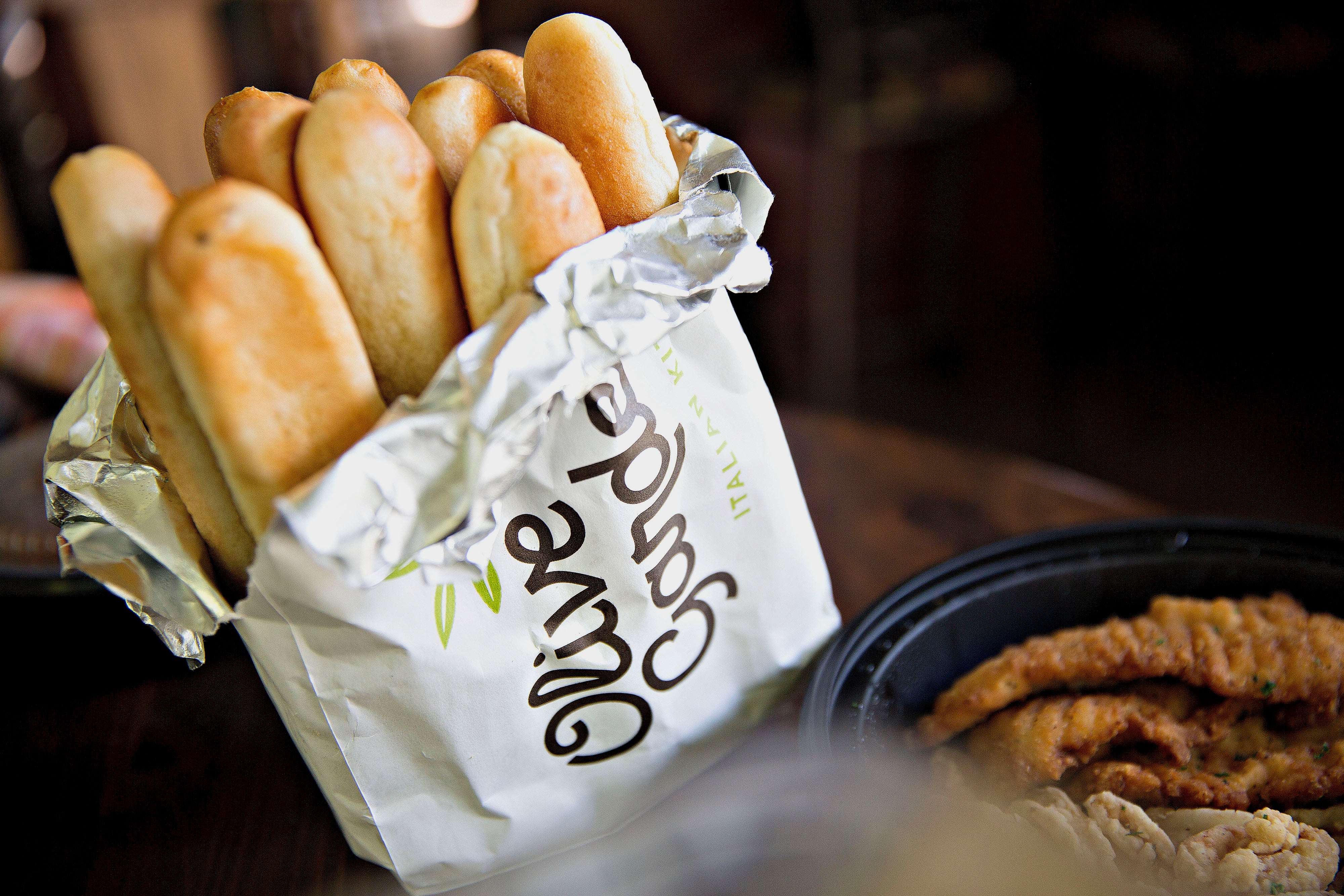 Olive Garden breadsticks wrapped successful foil, placed successful a branded insubstantial bag, with fried nutrient successful a achromatic instrumentality nearby