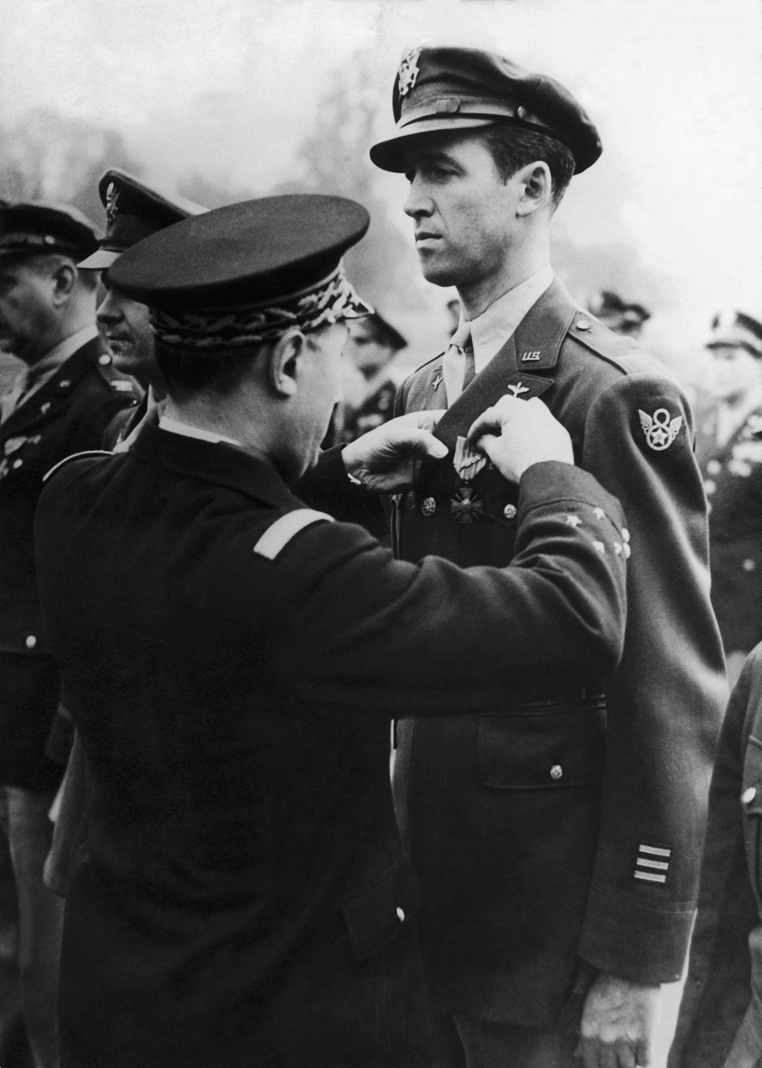 Jimmy Stewart in military uniform receives a medal from another officer during a formal ceremony