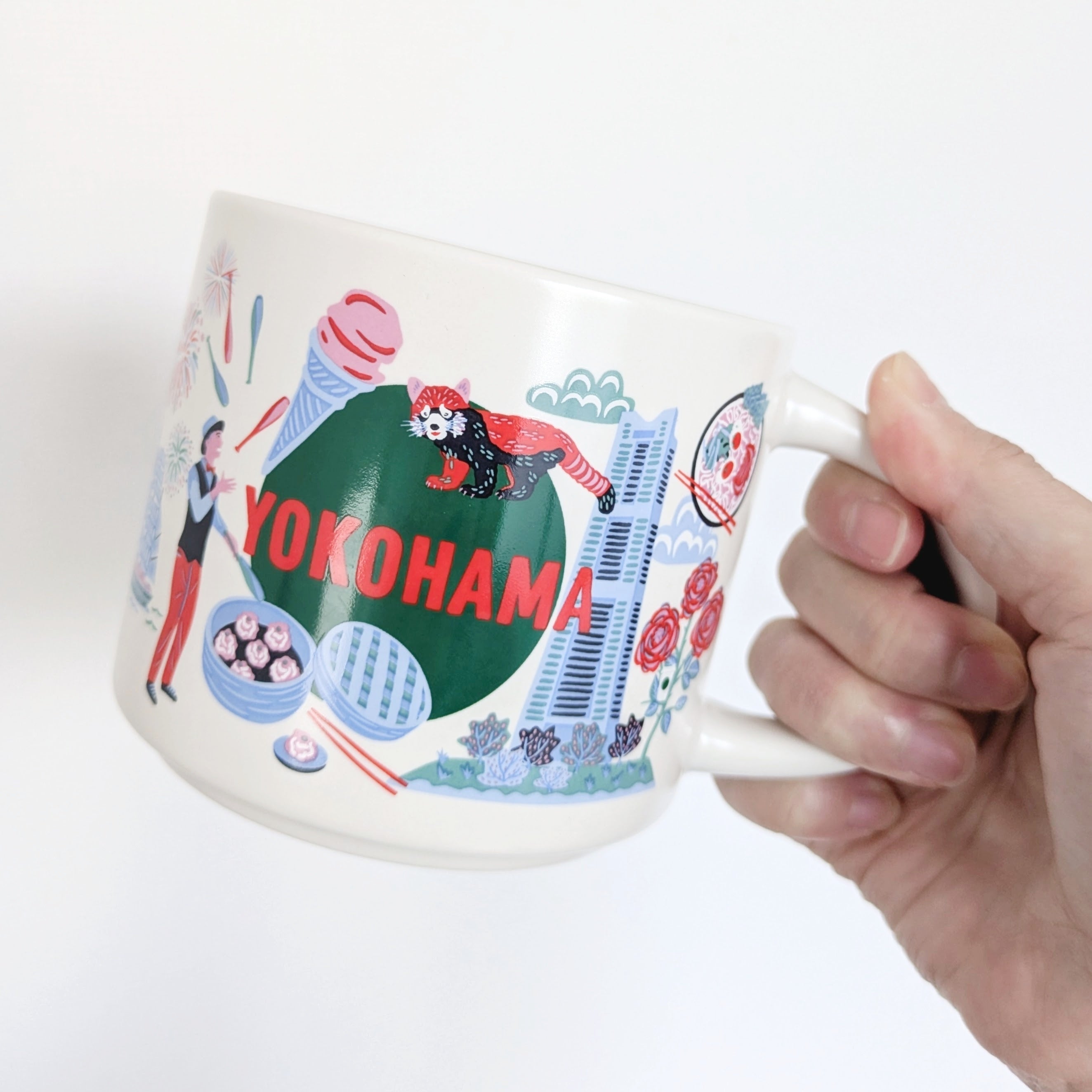スターバックス「Discovery Series マグYOKOHAMA414ml」手に持たれたマグカップには「YOKOHAMA」と書かれ、街のイラストがデザインされています。