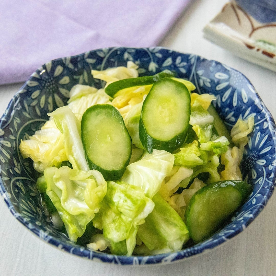 キュウリとキャベツのスライスが入った模様のついたボウルに盛られたサラダ。