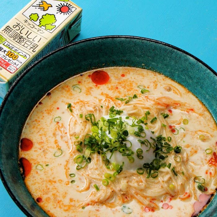 ラーメンの器に濃厚なスープとネギ、左に豆乳パックが置かれている食事の写真。